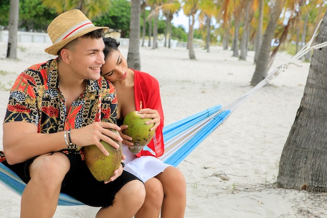 https://www.pexels.com/photo/couple-in-beach-holding-coconut-8249279/ alternativní text: žena a muž seznámení v létě na dovolené